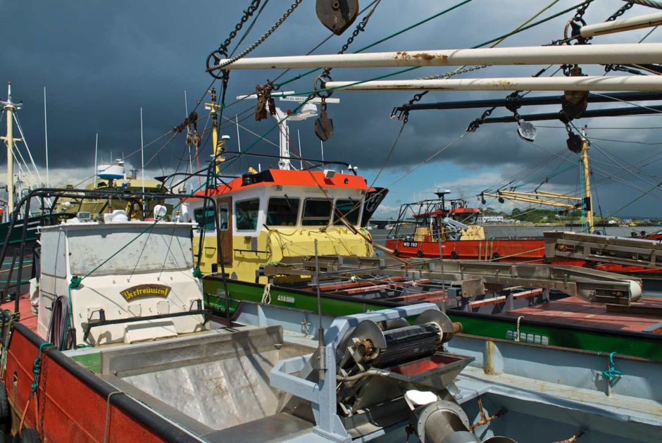 Kleurfoto van een marinehaven met fel gekleurde boten onder een dreigende hemel