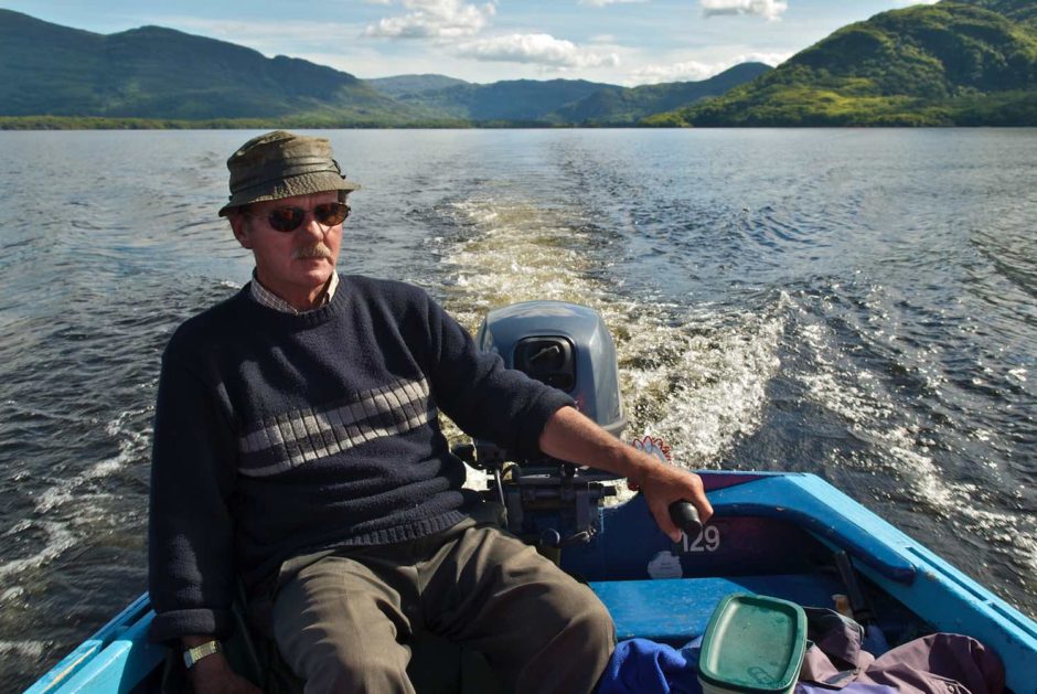 Kleurfoto van een man in een sloep met buitenboordmotor