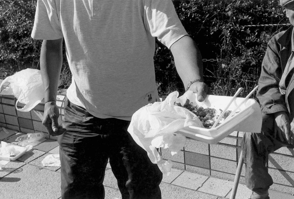 Zwart-wit foto van een dakloze de de fotograaf een hapje aanbiedt