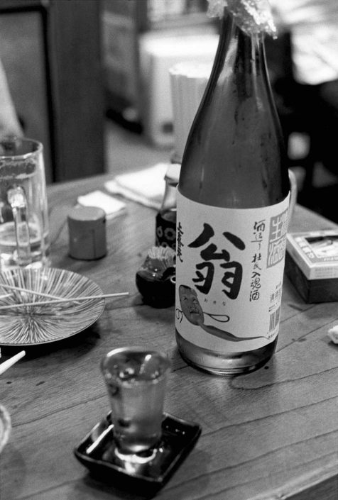 Zwart-wit foto van een geopende fles sake en een vol glaasje