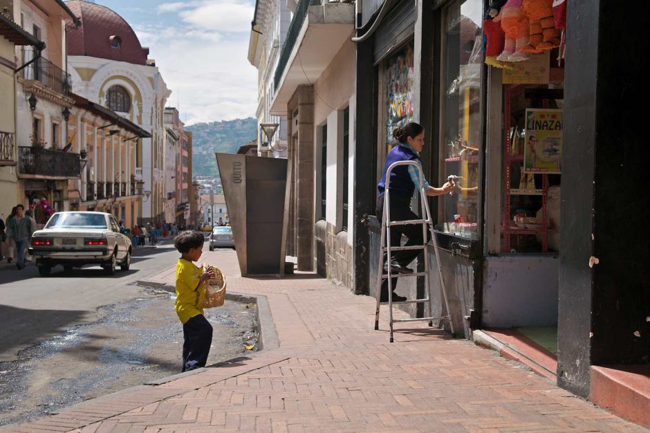 Kleurfoto van een jongedame die ramen lapt in het historisch centrum van Quito