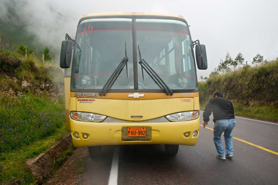 Kleurfoto van een gele bus die met motorpech lang de kant staat