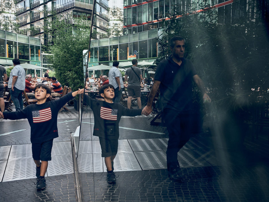 Kleurfoto van de reflectie van een jongetje aan de hand van zijn vader