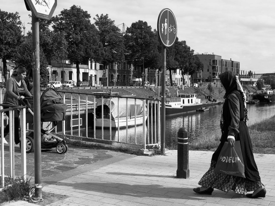 Zwart-wit foto van een een gesluierde dame aan de voetgangersbrug aan de Groendreef in Gent