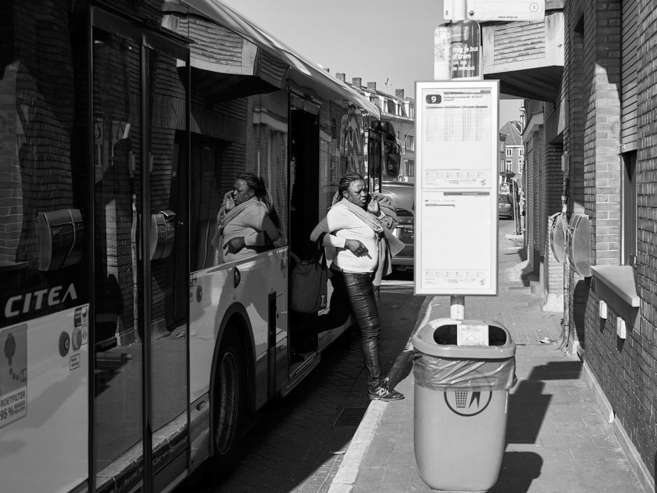 Zwart-wit foto van een gekleurde dame die van de bus stapt