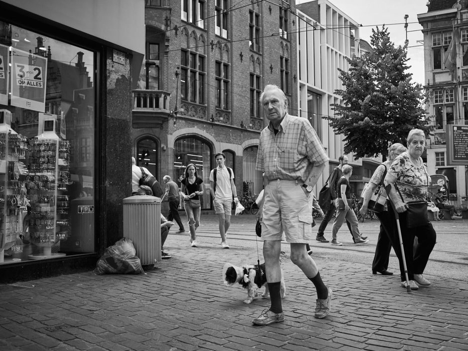 Zwart-wit foto van een oudere man met hondje op de Korenmarkt in Gent