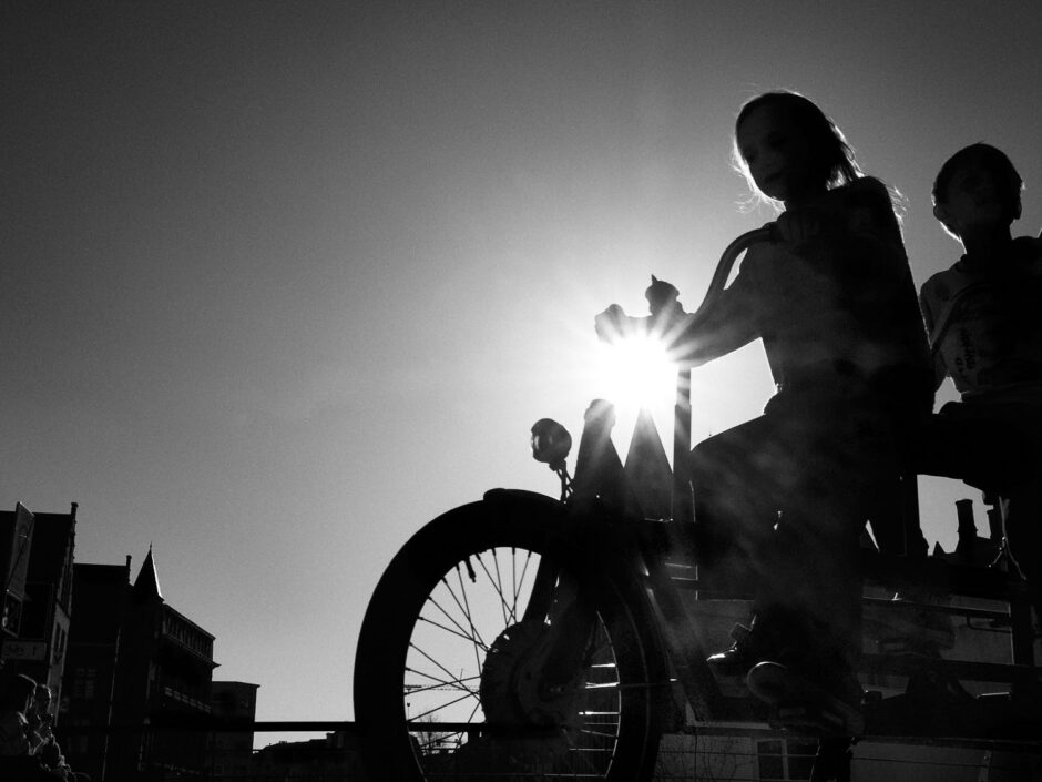 Black & white street photography of homo urbanus, more precisely of two youngsters on a tandem bike in back light