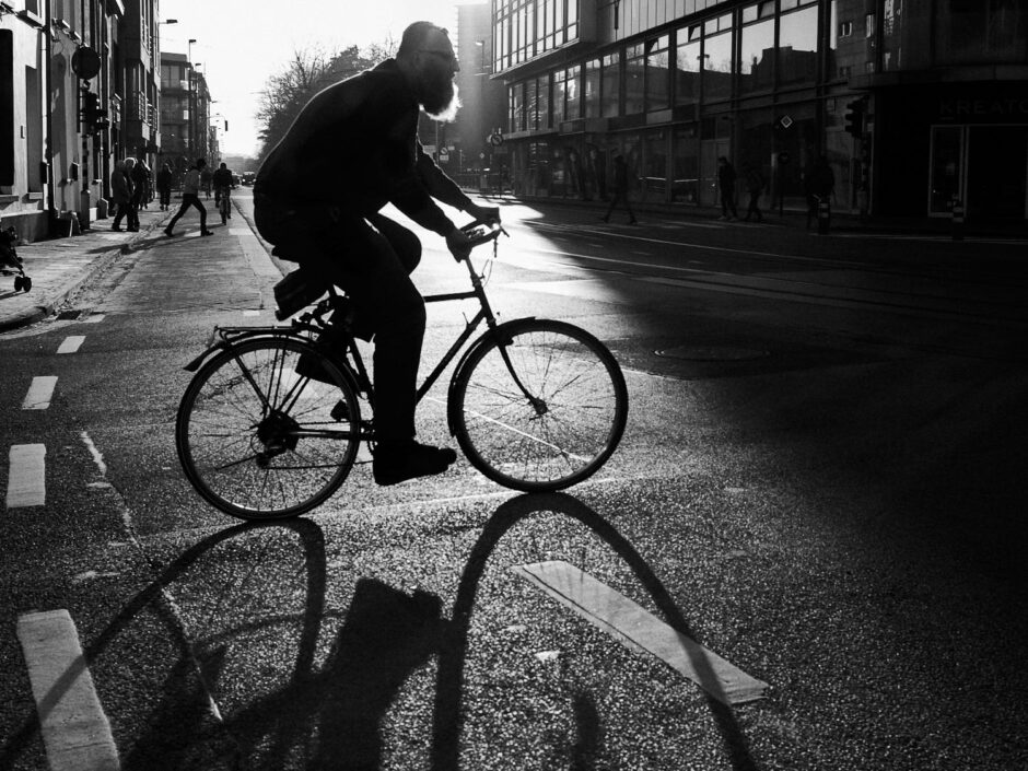 Black & white street photography of homo urbanus, more precisely of a bearded cyclist in back light sunburst