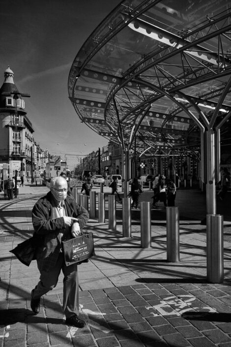 Black & white street photography of homo urbanus, more precisely of a man looking at his watch in front of a train station