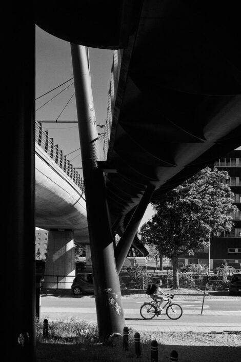 Black & white street photography of homo urbanus, more precisely of a lonely bicycle rider under a huge flyover