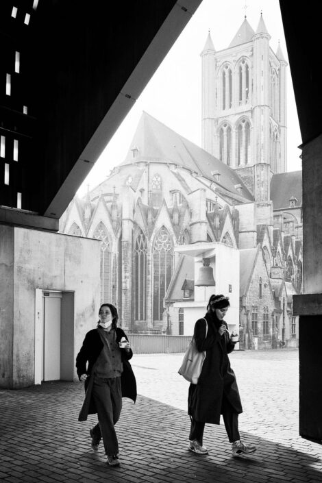 Black & white street photography of homo urbanus, more precisely of two young women with an ice-cream in front of the St Nicholas' Church in Ghent