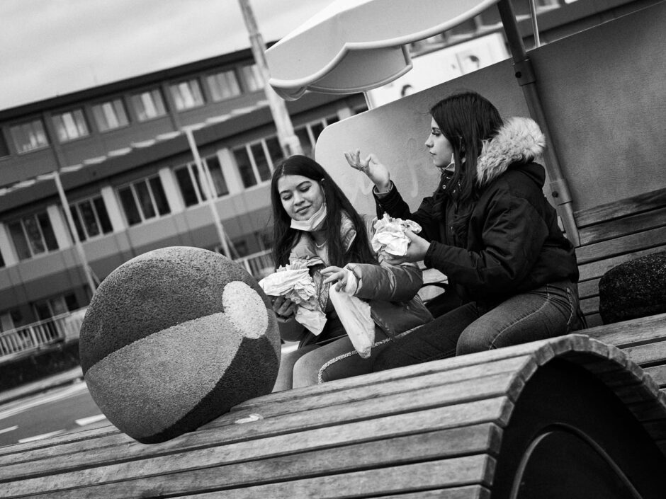 Black & white street photography of homo urbanus, more precisely of two young women enjoying a quick snack