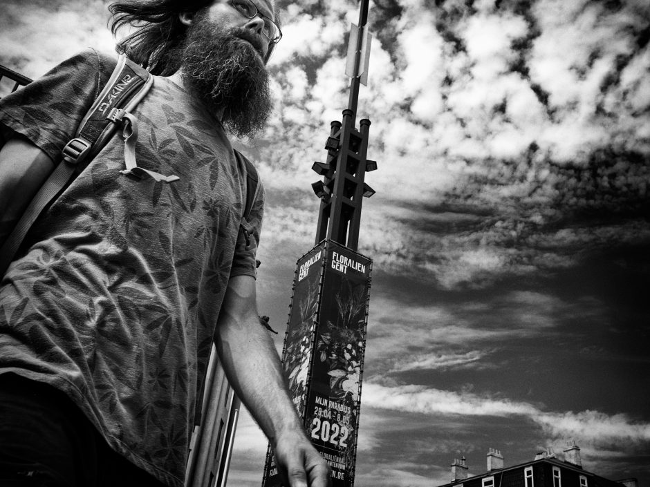 Black & white photograph of a young man with a long beard, taking from a low vantage point