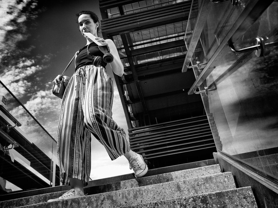 Black & white photograph of a young woman descending a staircase with a letter in her hand