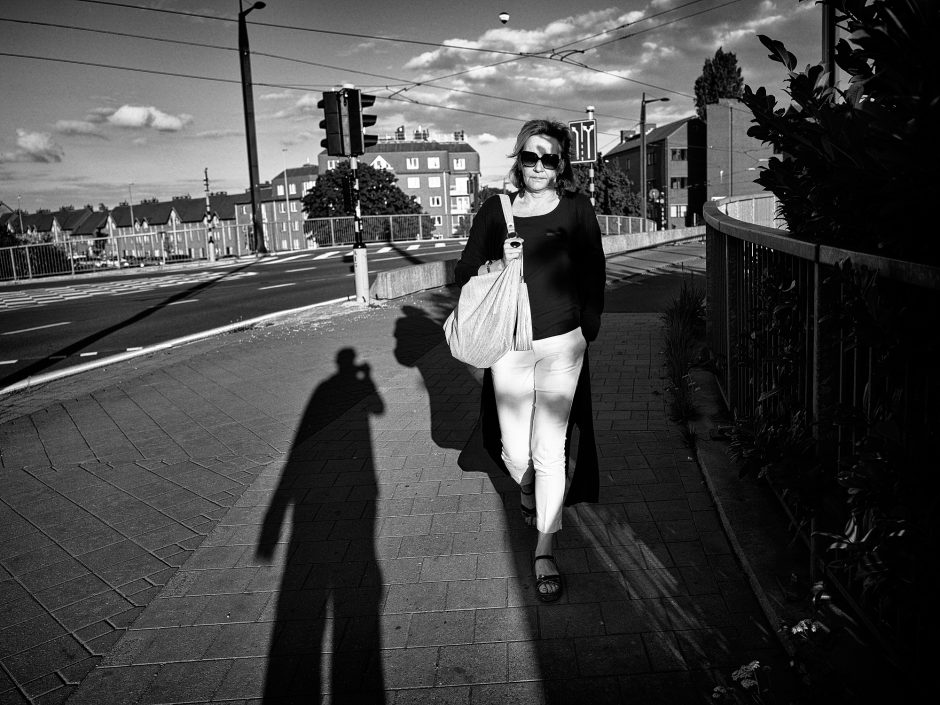 Black & white photograph of a lady on a evening stroll and the shadow of the photographer