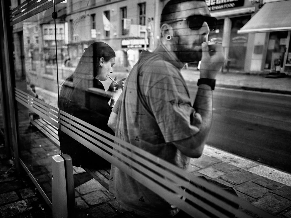 Black & white photograph young couple in a bus stop, with smoking a cigarette